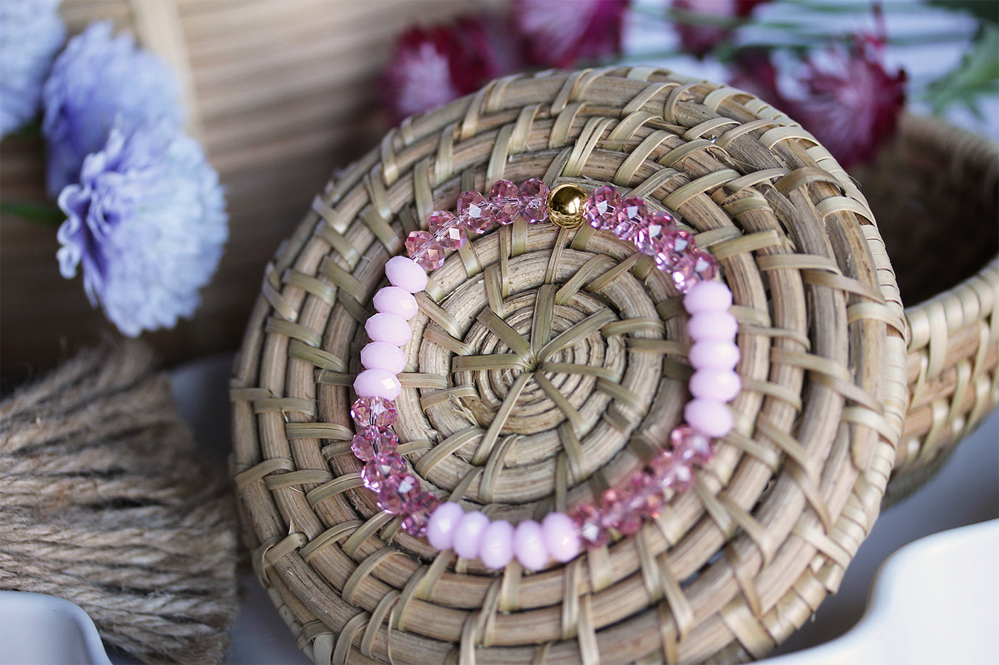 Swarovski Crystal Elements - Pink Stretch Bracelet on basket surrounded by flowers. 