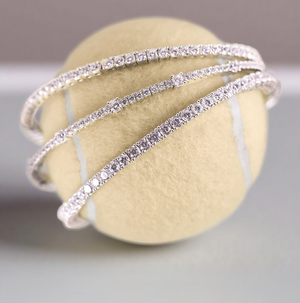 Lafonn simulated diamond tennis bracelets in sterling silver, elegantly wrapped around a tennis ball. Timeless and sparkling tennis bracelet designs that bring everyday luxury and classic style.