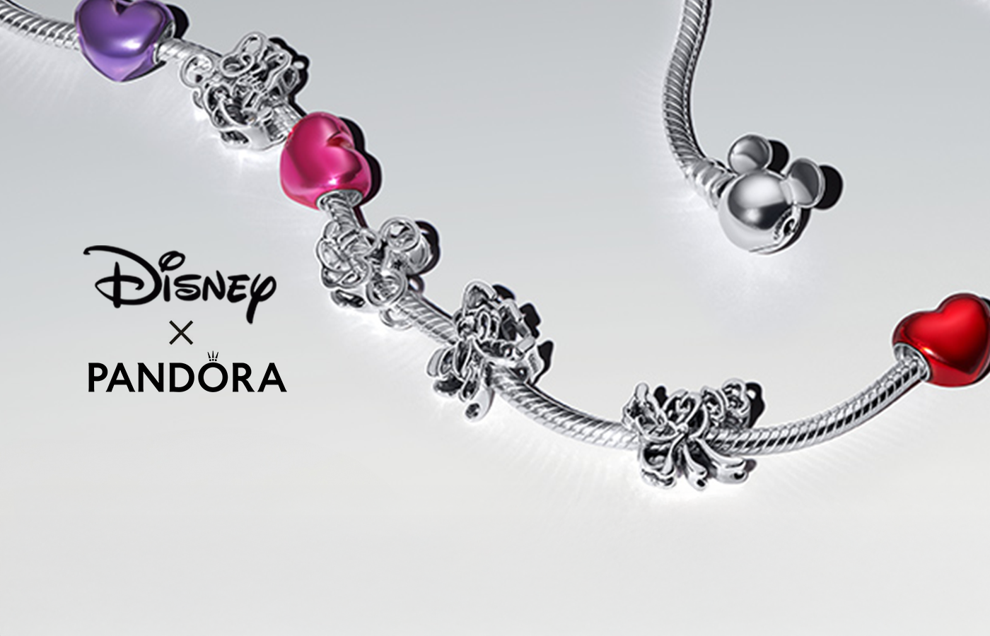 Disney x Pandora charm bracelet featuring sterling silver Minnie Mouse and Mickey Mouse charms, colorful heart-shaped enamel beads in red, pink, and purple, and a Mickey Mouse-shaped clasp on a sleek snake chain design.