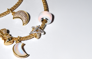 Close-up of Pandora gold charm bracelet featuring celestial-themed charms including pavé crescent moons, a glowing opalescent bead, and a crystal-encrusted star — a radiant mix of textures and symbols perfect for personalized holiday gifting.