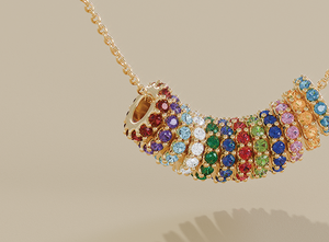 Colorful birthstone charm wheels in gold settings, each adorned with vibrant gemstones representing all twelve months, displayed on a delicate gold chain for a personalized jewelry look.