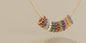 Colorful birthstone charm wheels in gold settings, each adorned with vibrant gemstones representing all twelve months, displayed on a delicate gold chain for a personalized jewelry look.