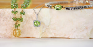 Elegant peridot jewelry featuring a green gemstone pendant with diamond halo, a gold and green beaded necklace, and a silver woven bracelet with a faceted peridot bead, displayed on a marble surface — perfect for August birthstone gifts or summer jewelry inspiration.