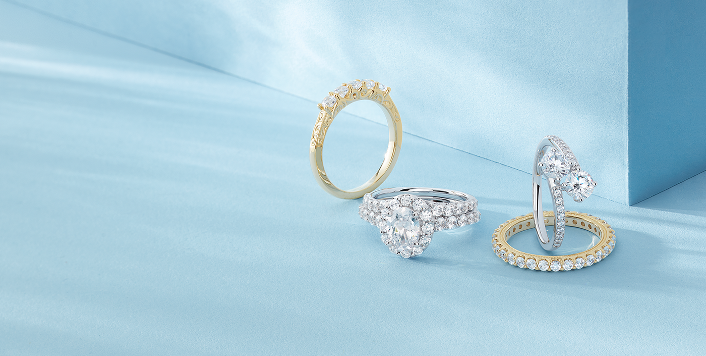Radiant white gold and gold engagement rings with stunning diamond wedding bands on a teal background, featuring beautiful shadows - where your 'I do' comes true.